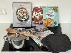 Auf einem Herd liegen vier Kochbücher. Außerdem steht ein Topf auf dem Herd und Topflappen liegen neben dem Topf.